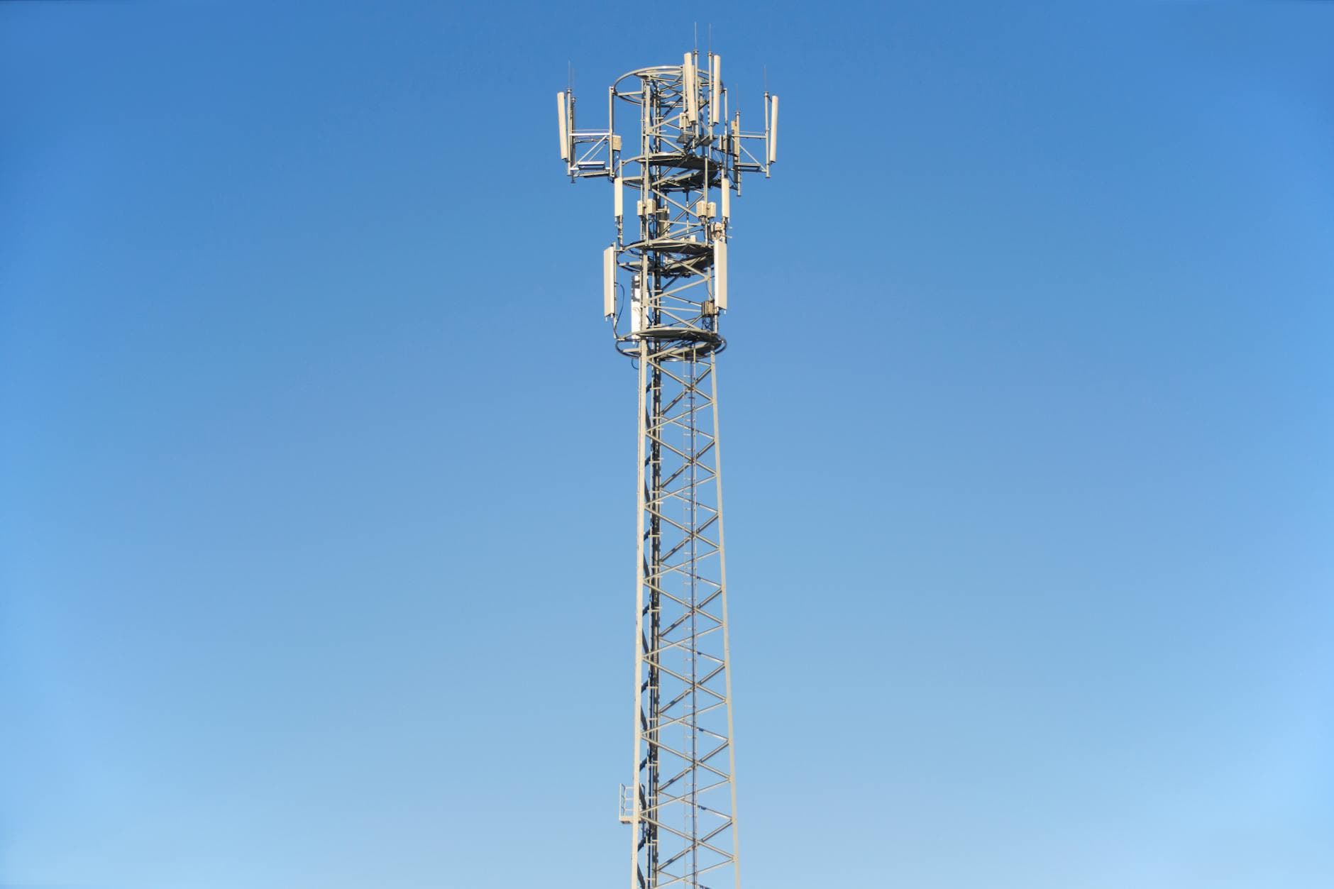 A tall cell tower set against a clear blue sky, representing modern communication technology.