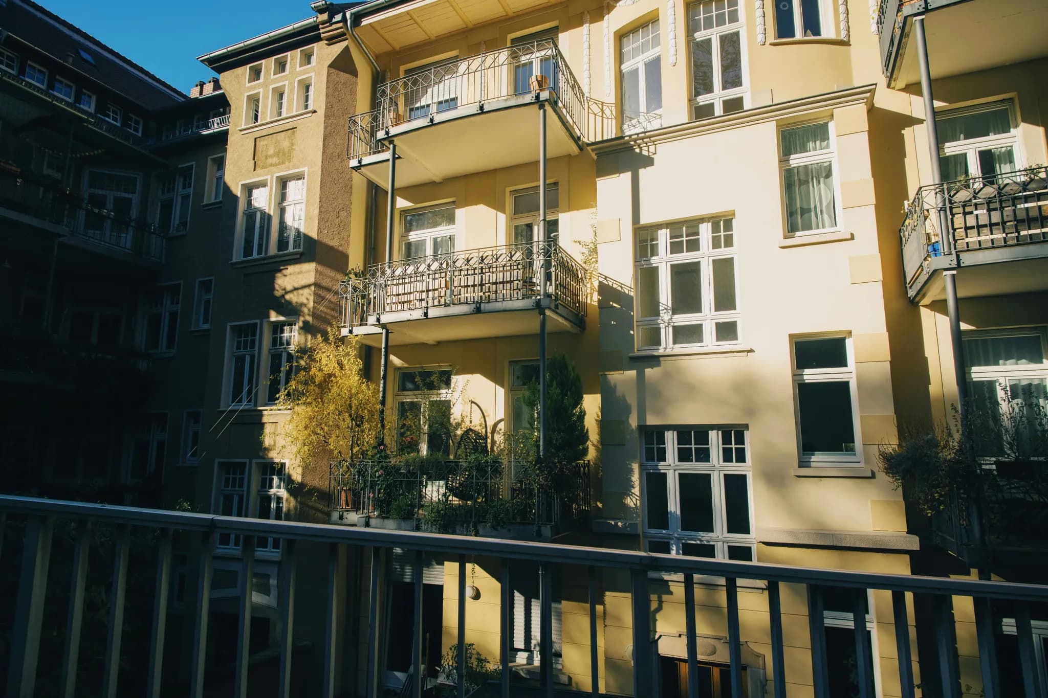 Yellow apartment building with balconies and windows.