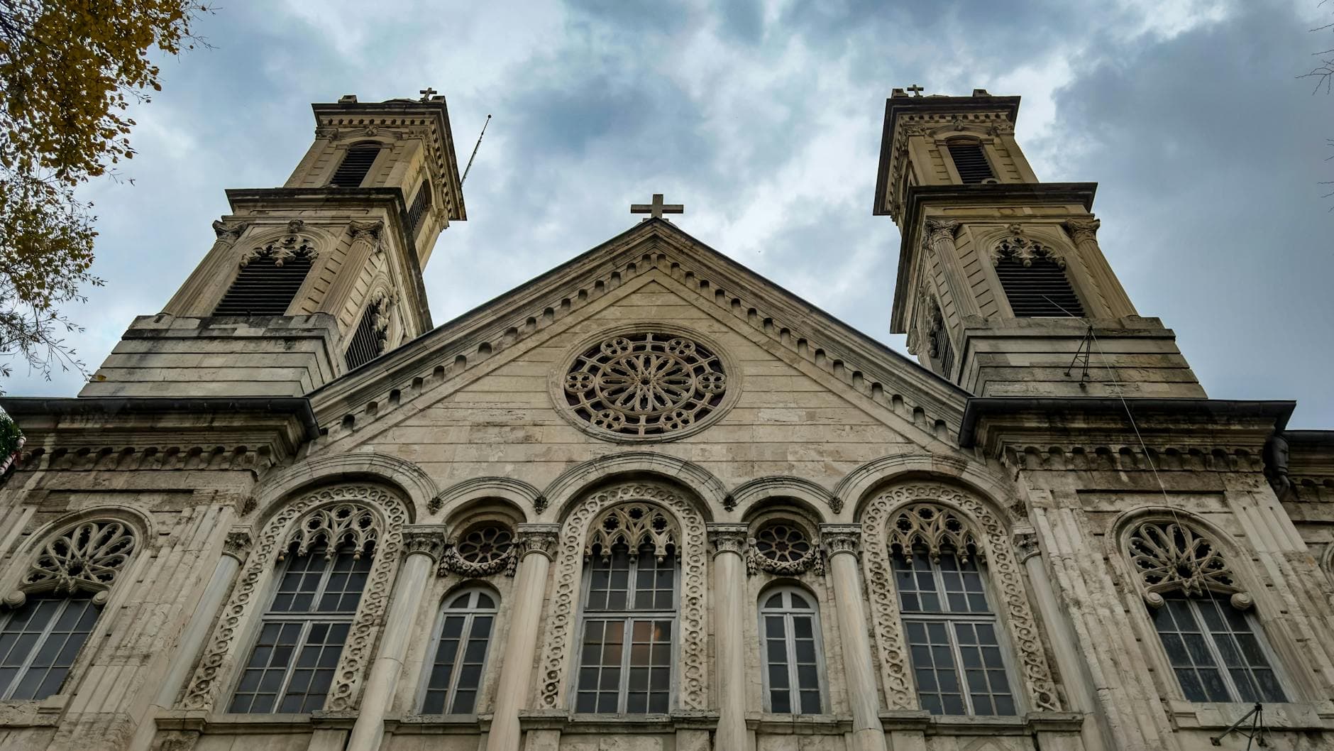 Beautiful historic church facade in İstanbul, Türkiye, featuring Gothic architecture against a dramatic cloudy sky.