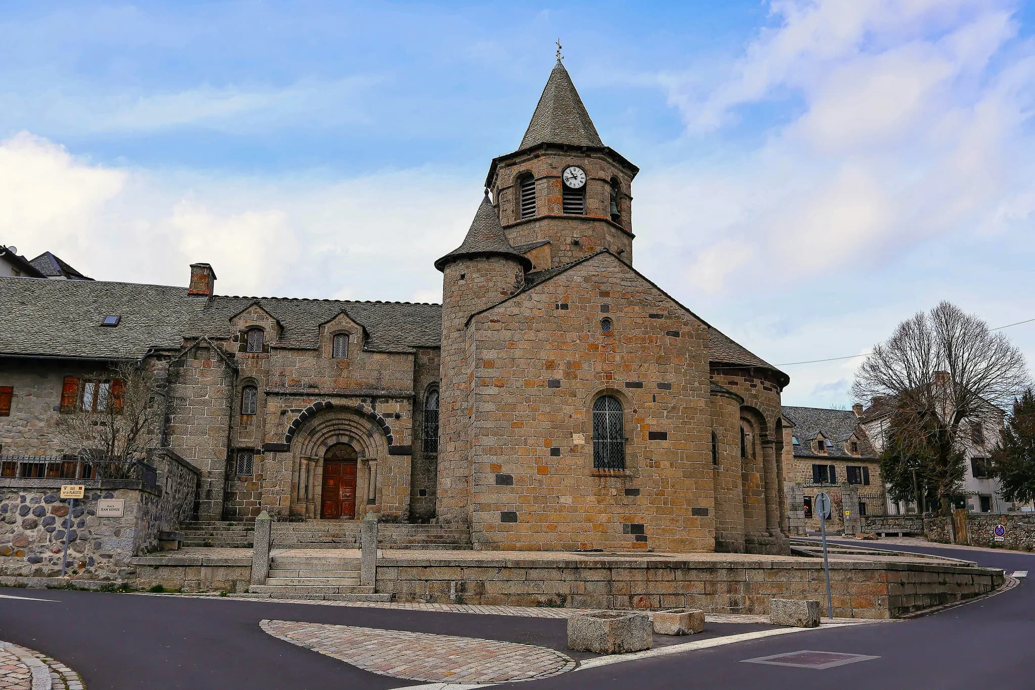 Stone church with a tall spire under a cloudy sky.