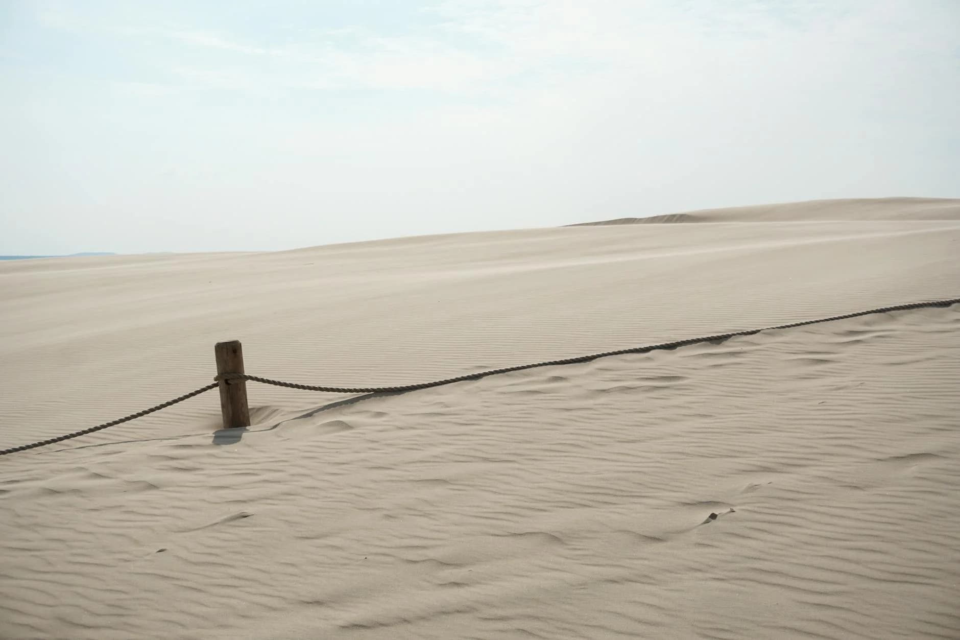 A tranquil view of sand dunes at Słowiński National Park, Poland, under a clear sky.