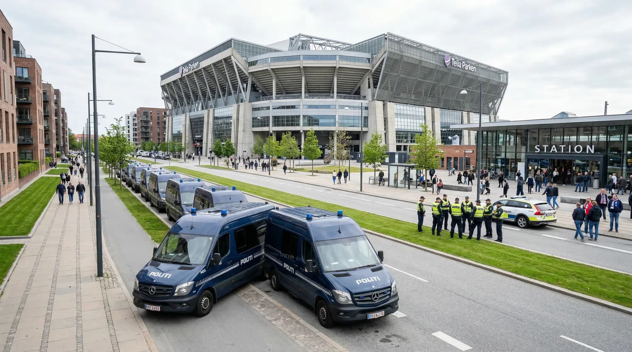 A line of dark blue police transport vans parked along a modern suburban street near a large sports stadium. The scene is captured with a wide-angle lens in soft, natural daylight, showing a clean nor