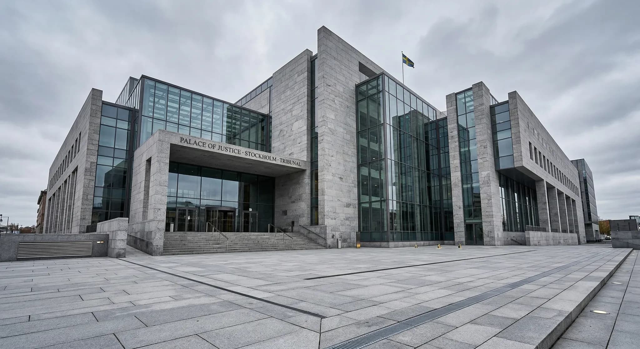 A wide-angle architectural shot of a modern European courthouse constructed from light grey stone and large glass panels. The building is captured from a low angle against a soft, overcast Scandinavia