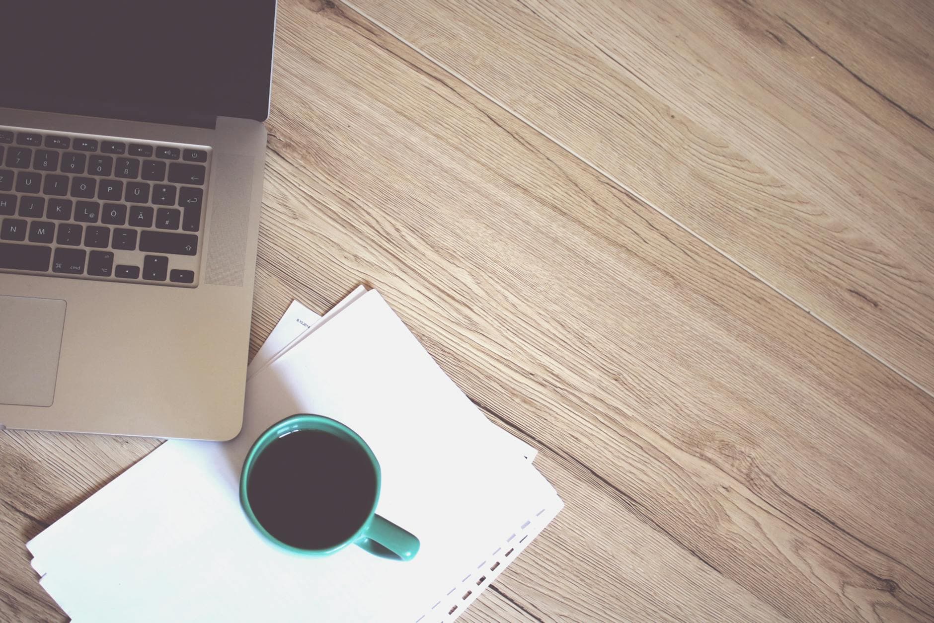 A minimalist workspace featuring a coffee cup, laptop, and wooden desk, offering a productive and stylish environment.
