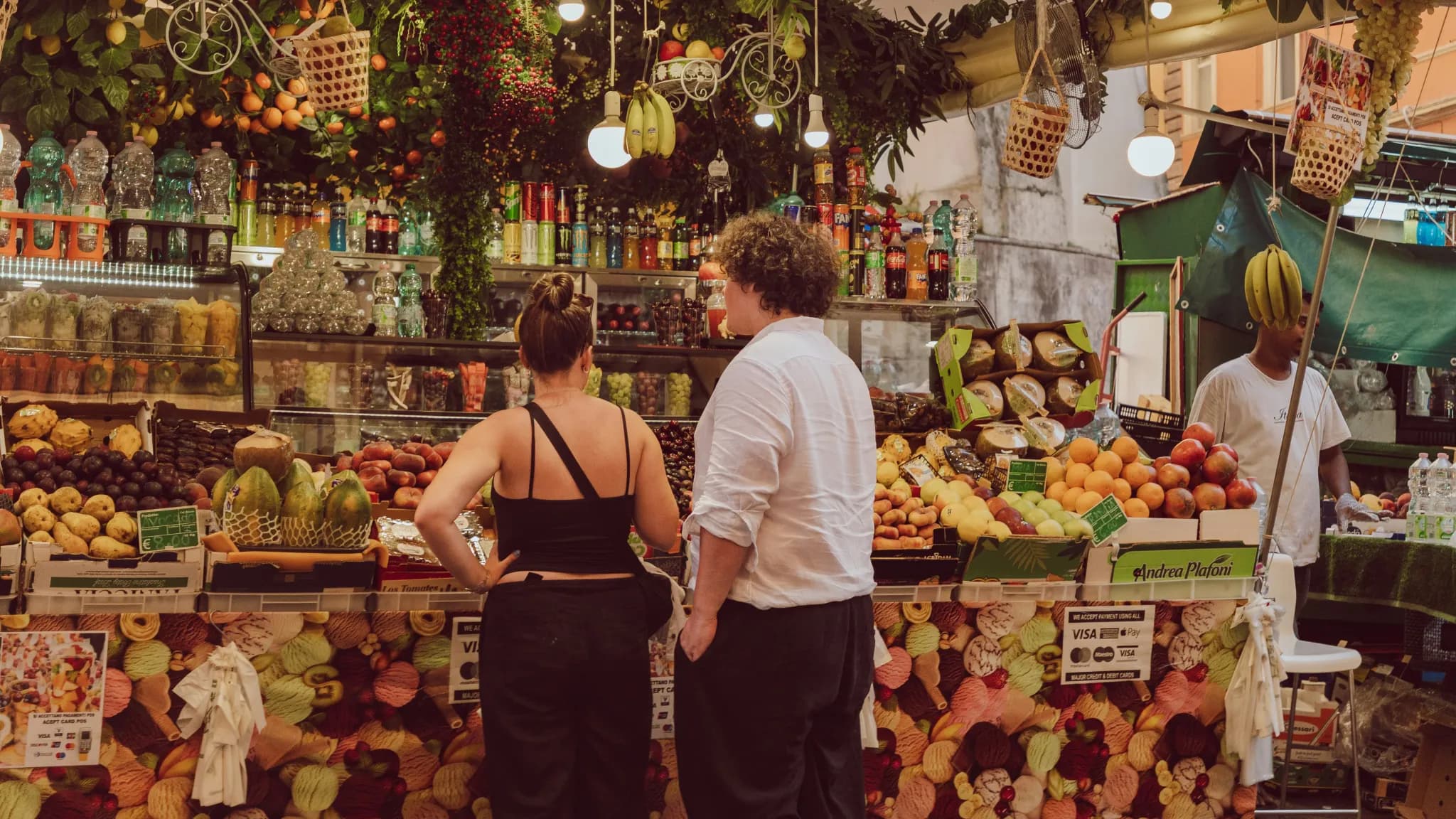 People browsing a vibrant fruit and vegetable market stall.