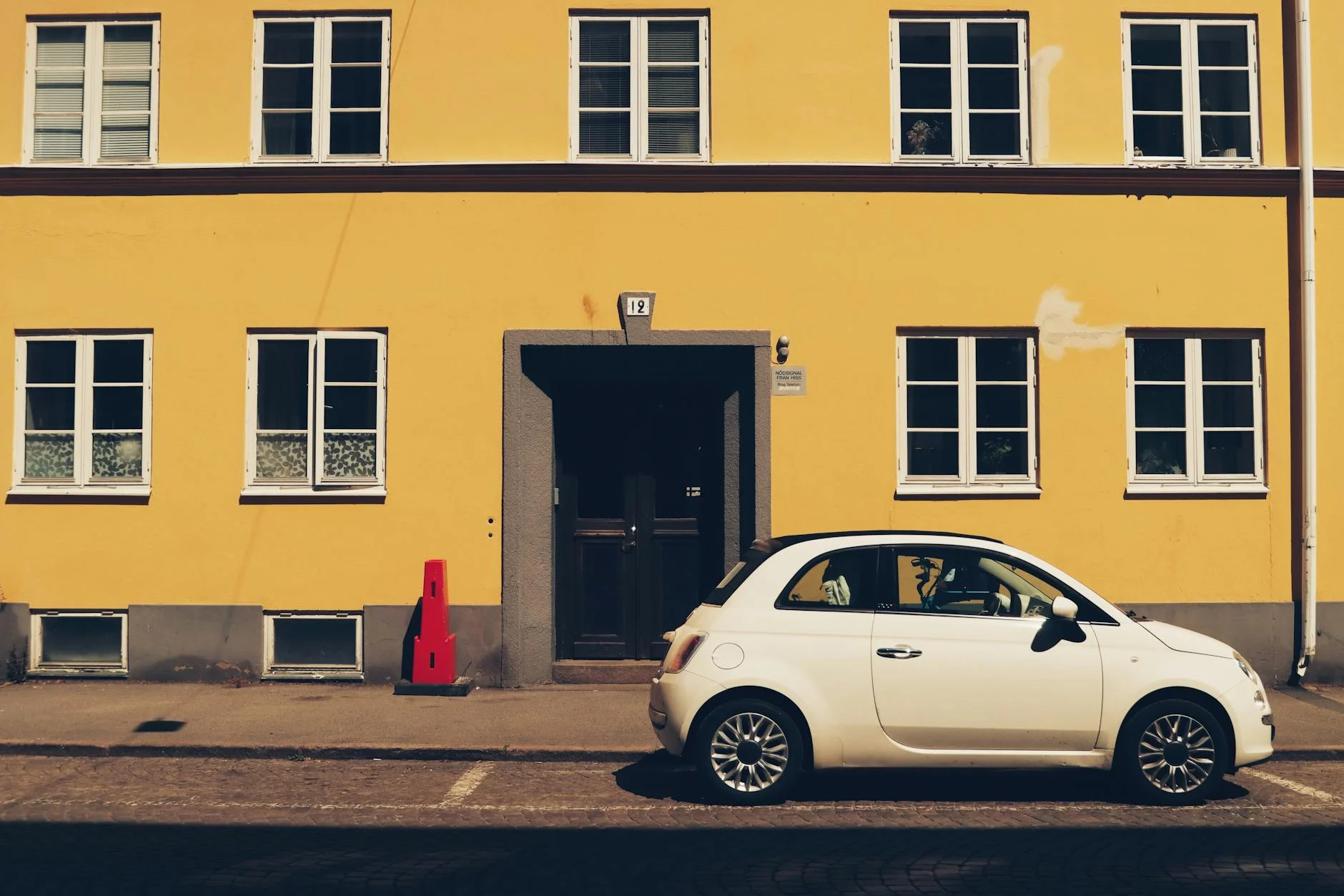 White Fiat parked in front of a yellow building on Jönköping street, Sweden.