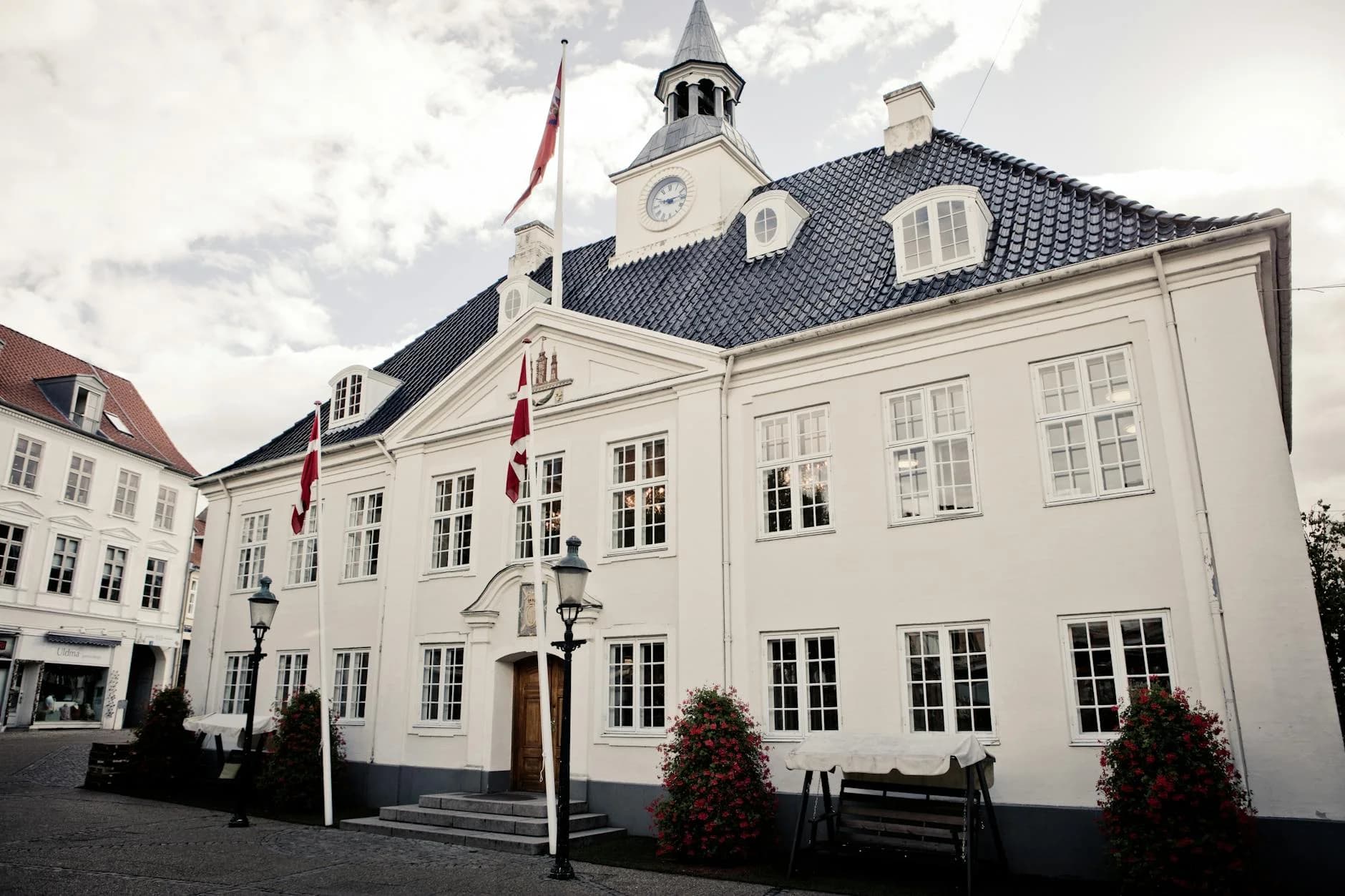 Elegant white town hall building with flags on display, showcasing classic architecture.