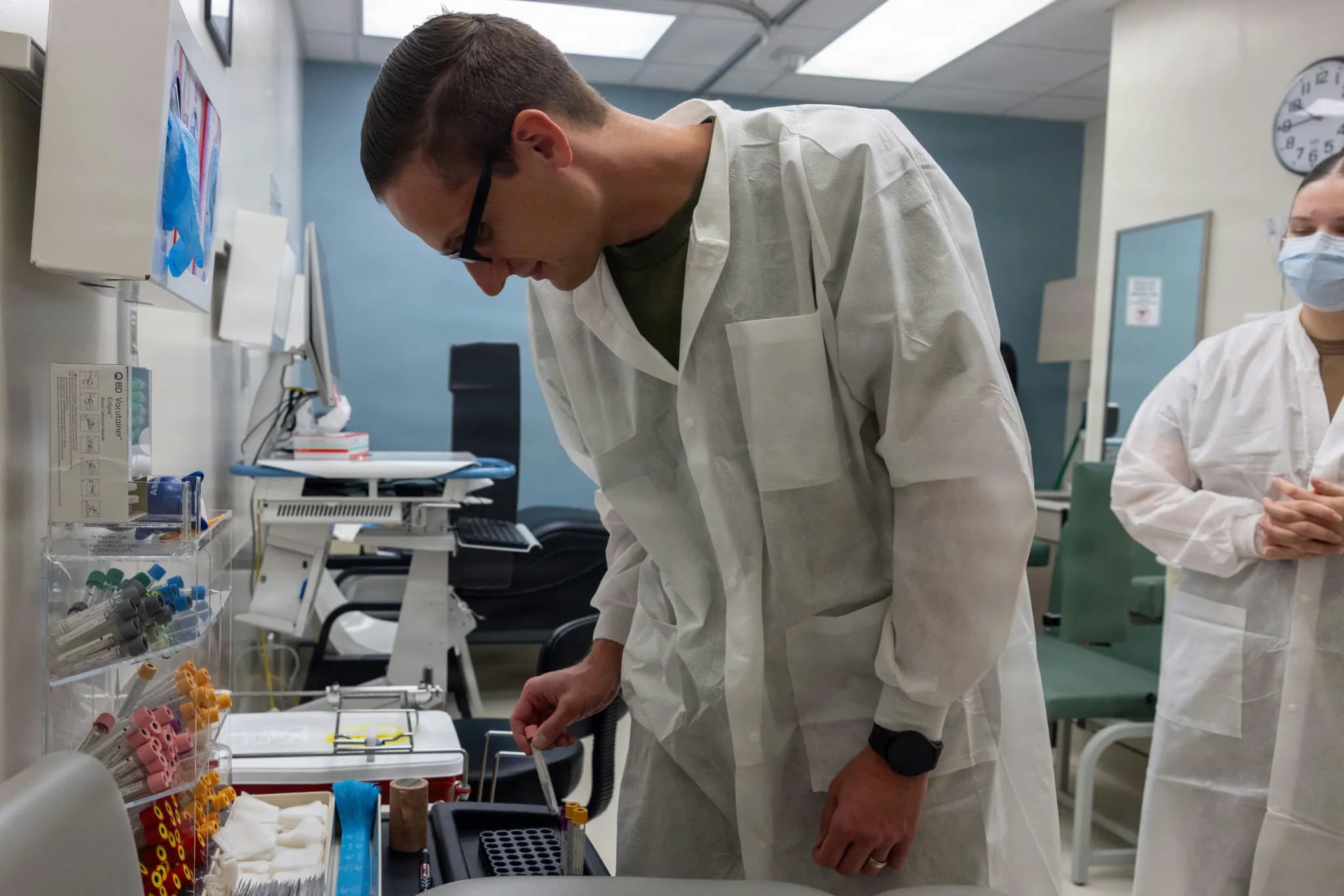 Scientist in lab coat examines sample in laboratory.