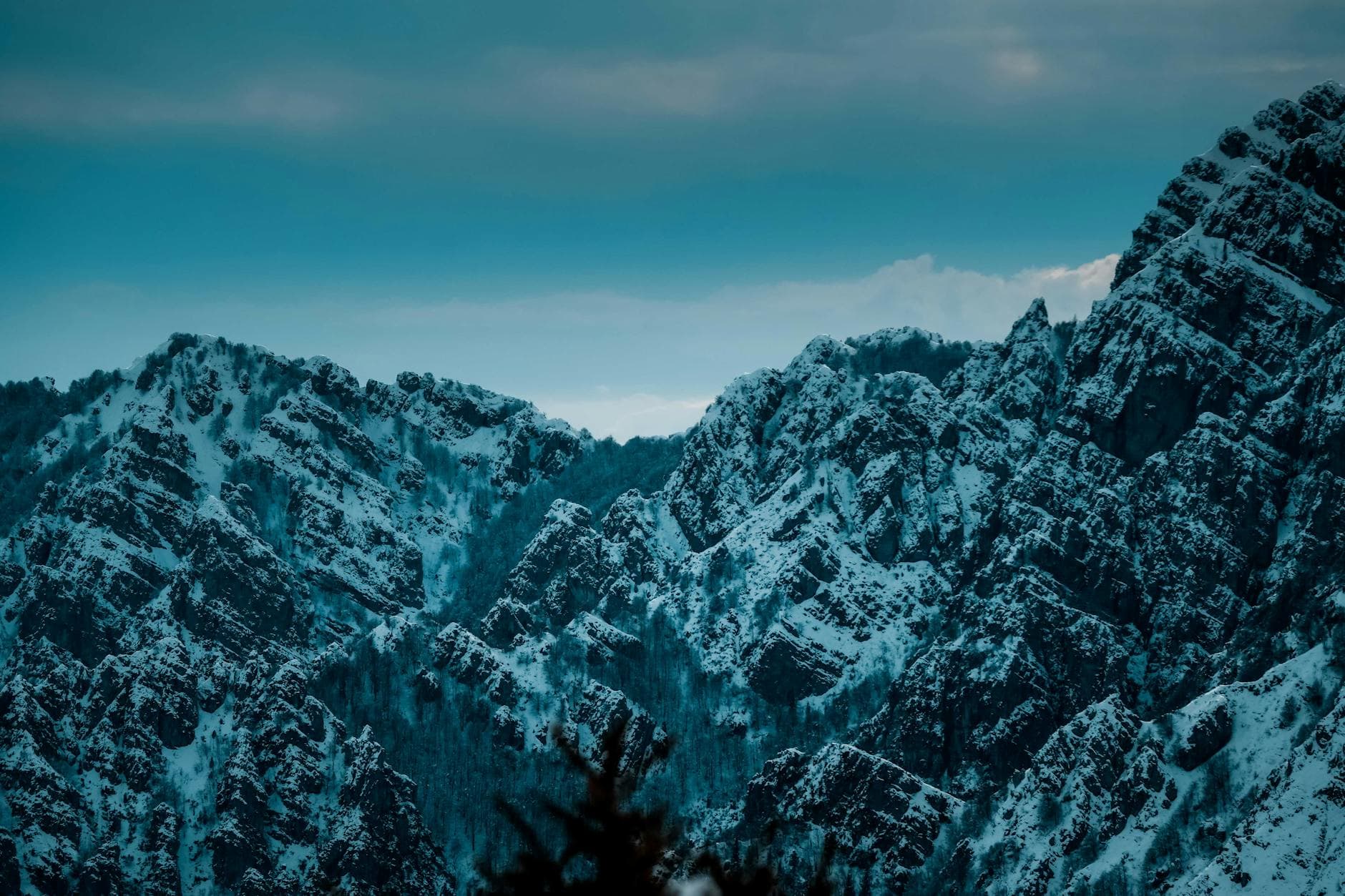A dramatic snow-covered rocky mountain landscape captured at dusk, emphasizing the natural beauty and tranquility.