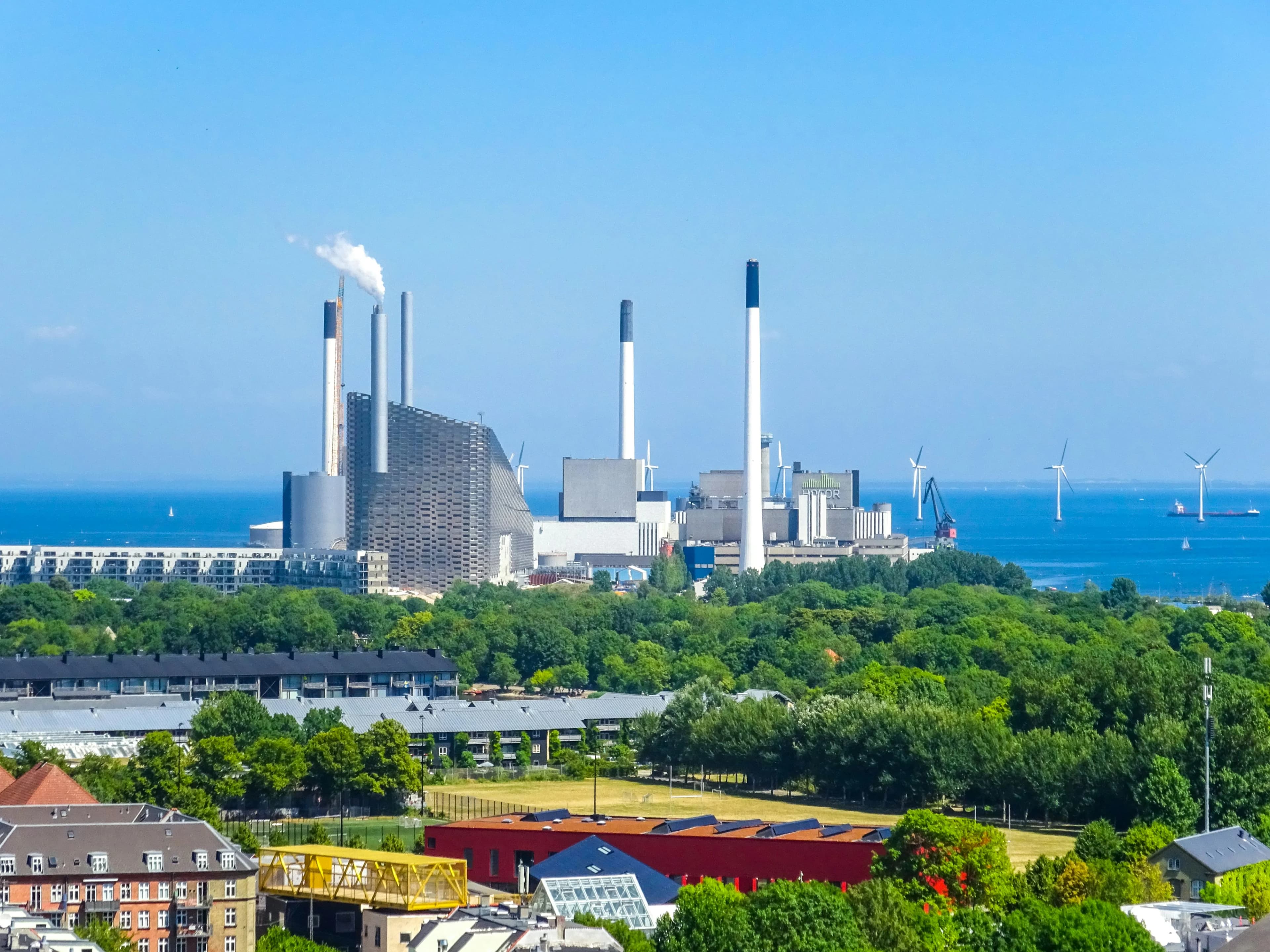 Industrial power plant with smokestacks by the ocean.