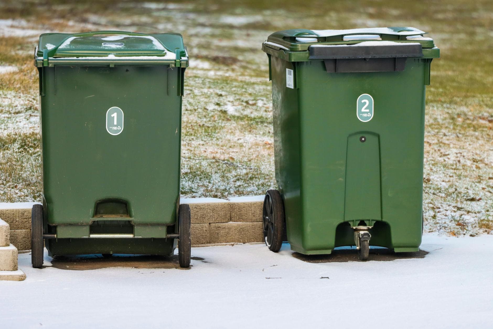 Two green garbage bins on a snowy day in Jönköping, Sweden.