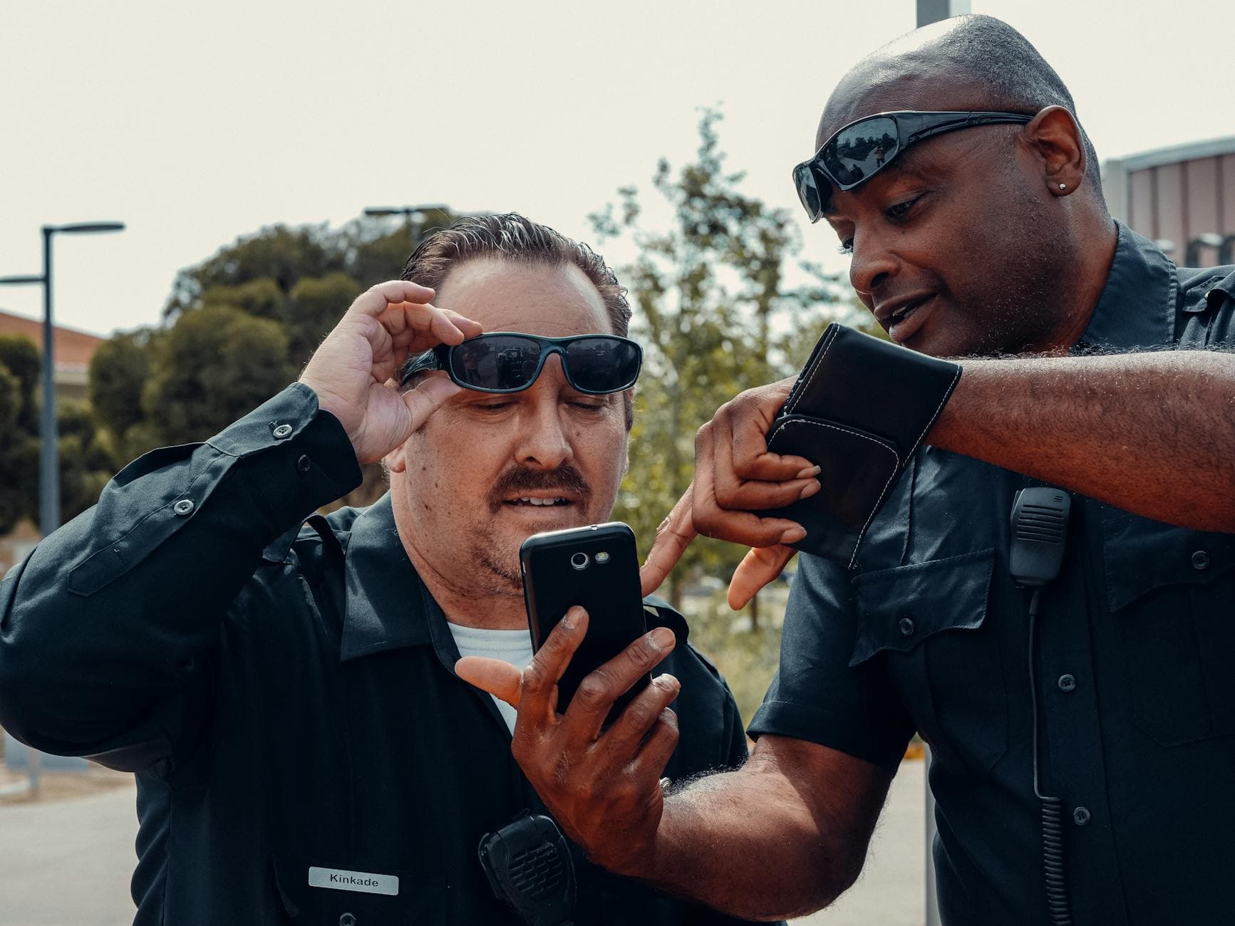 Two police officers analyzing information on a smartphone outdoors.