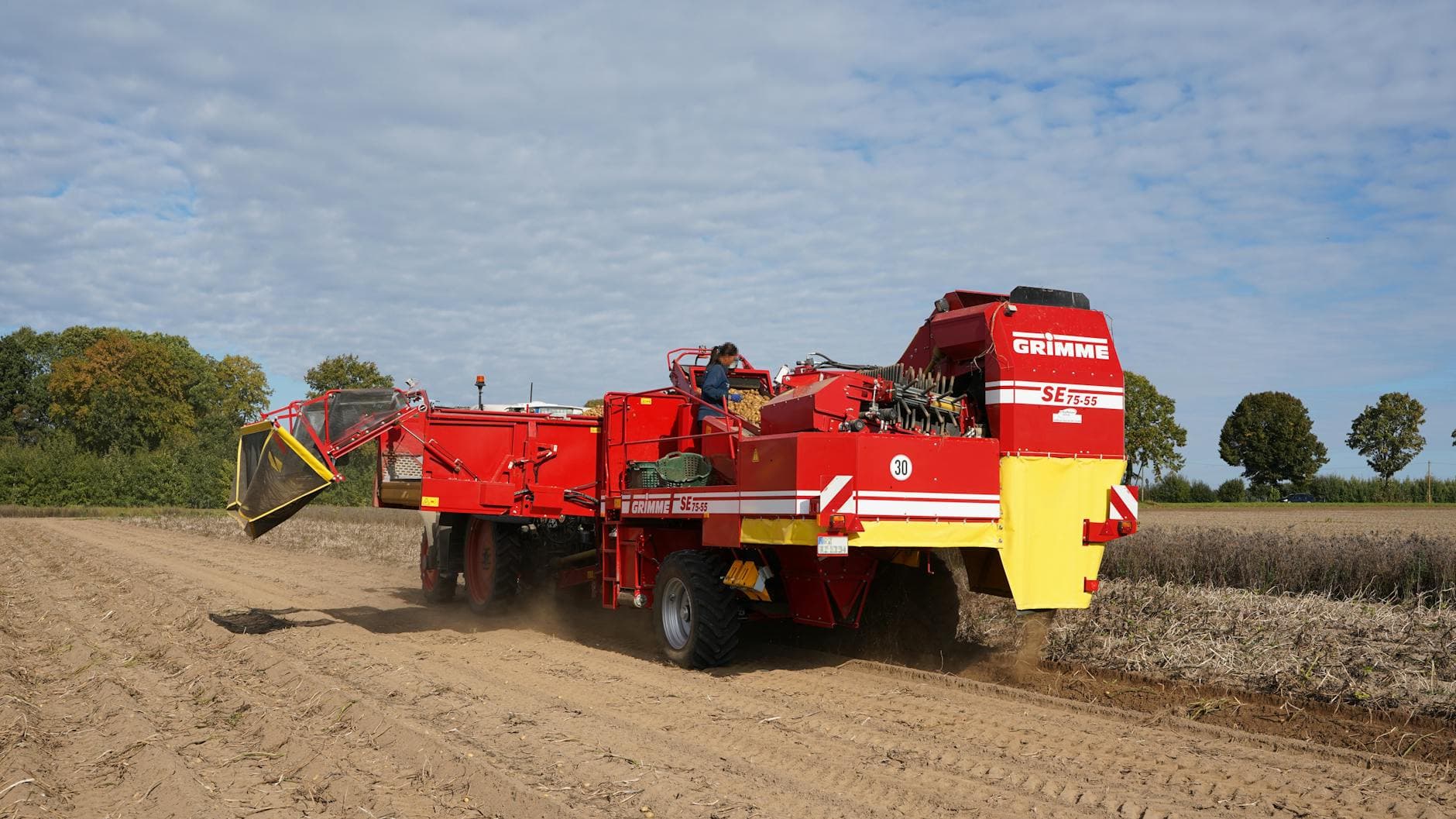 A vibrant red potato harvester operates in Hohenhorn, capturing the essence of autumn farming.