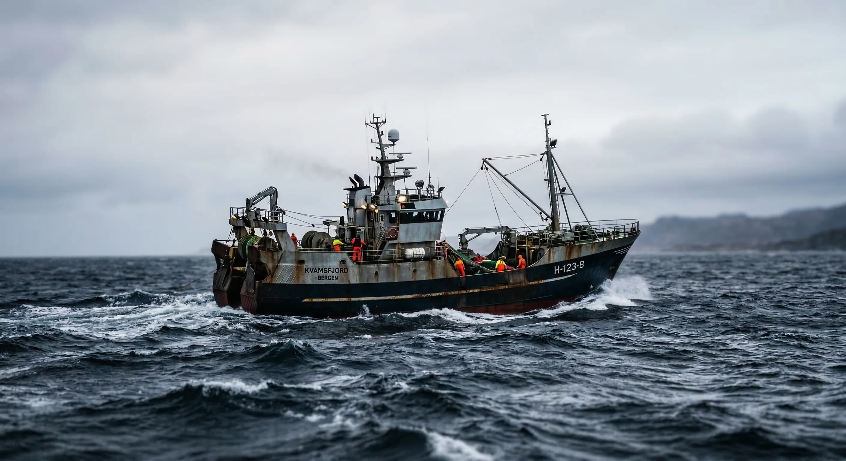 A rusty industrial fishing trawler navigates choppy, deep-blue waters under a pale, overcast sky. The vessel, identified as the "KVAMSFJORD," is actively crewed and set against a backdrop of distant, hazy coastlines, creating a moody and rugged maritime atmosphere.