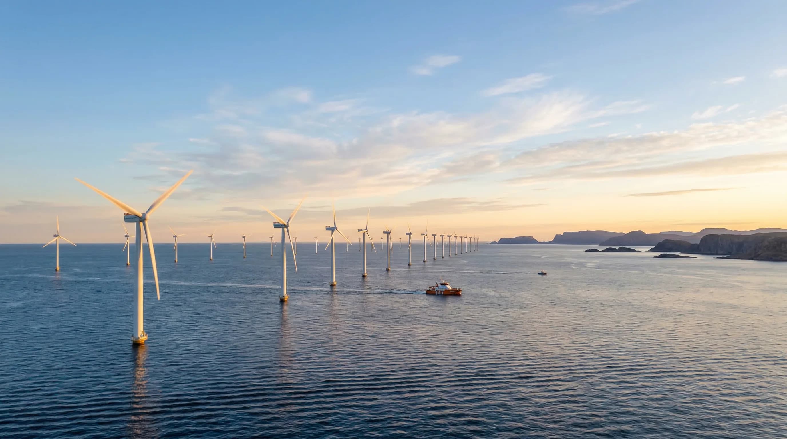A wide-angle photorealistic shot of massive offshore wind turbines standing in the deep blue waters of a Northern European sea. The scene is captured at dawn with soft, golden sunlight hitting the whi