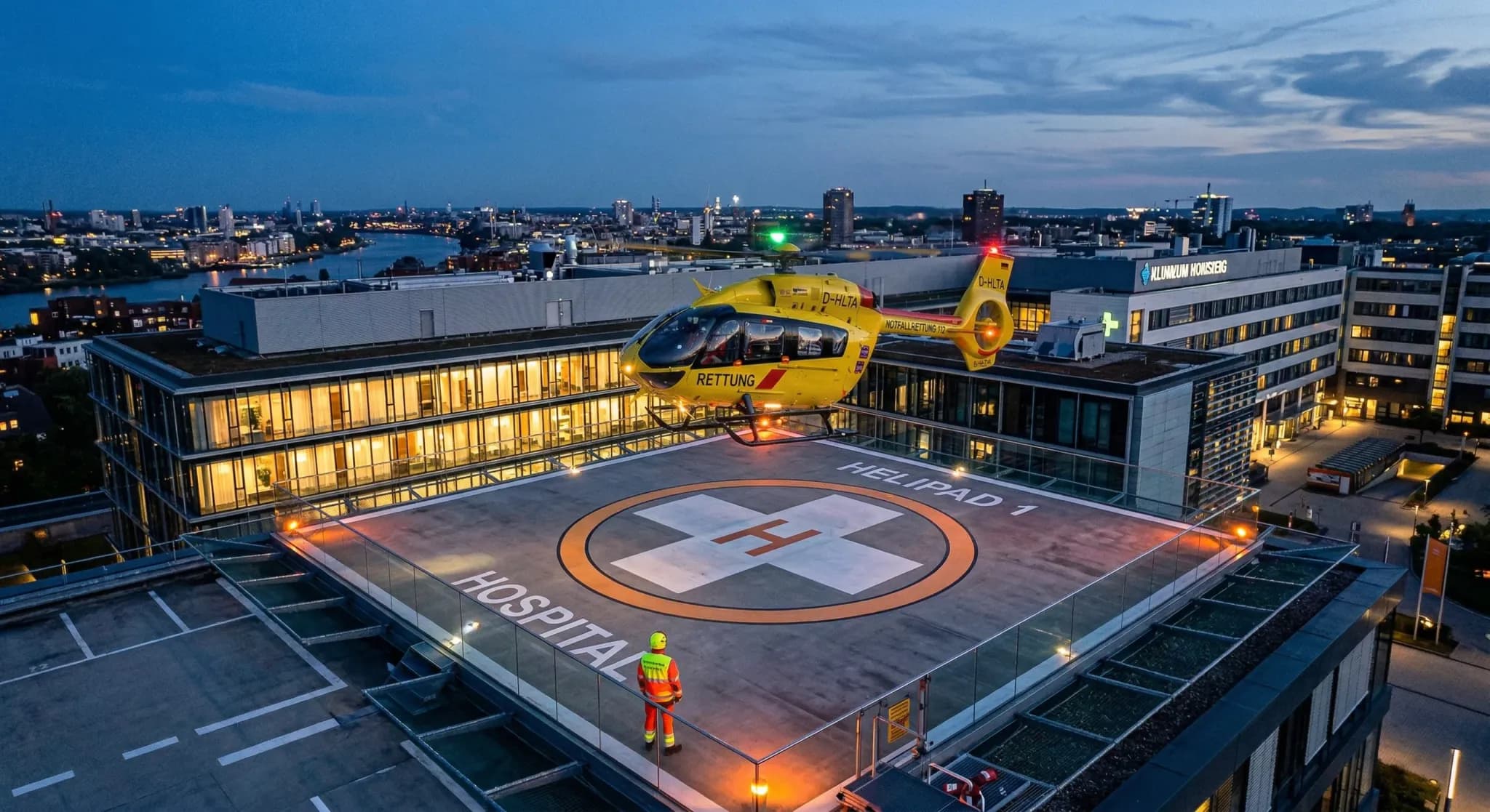 A photorealistic shot from a high angle looking down at a modern hospital rooftop helipad during twilight. A bright yellow emergency medical helicopter is hovering just inches above the landing surfac