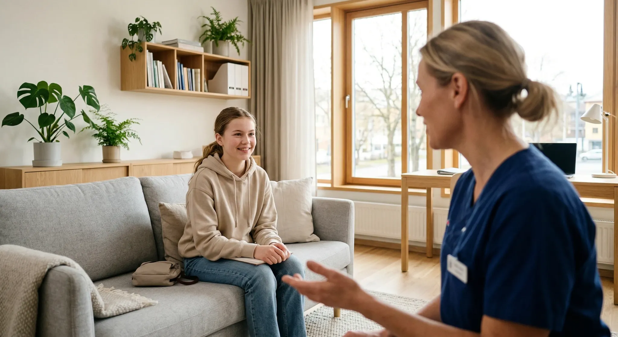 In a bright, modern office, a healthcare professional sits across from a smiling teenager, engaging in a gentle and supportive consultation. The room is decorated in a clean, minimalist style with light wood furnishings and indoor plants, creating a calm and welcoming atmosphere.