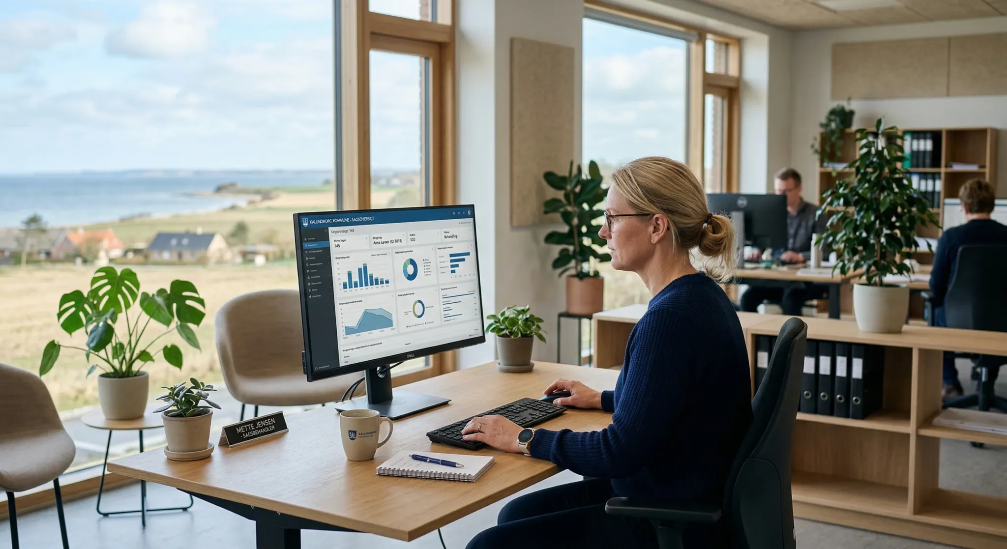 A photorealistic scene inside a modern Danish municipal office with large windows overlooking a blurred coastal landscape. A professional caseworker is focused on a computer screen displaying a clean,