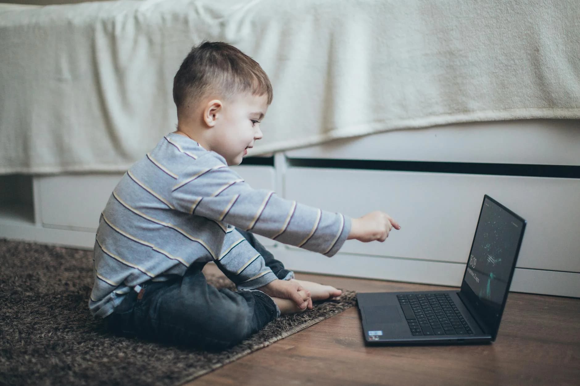 Young boy engaging with laptop, enjoying learning in a cozy home setting.