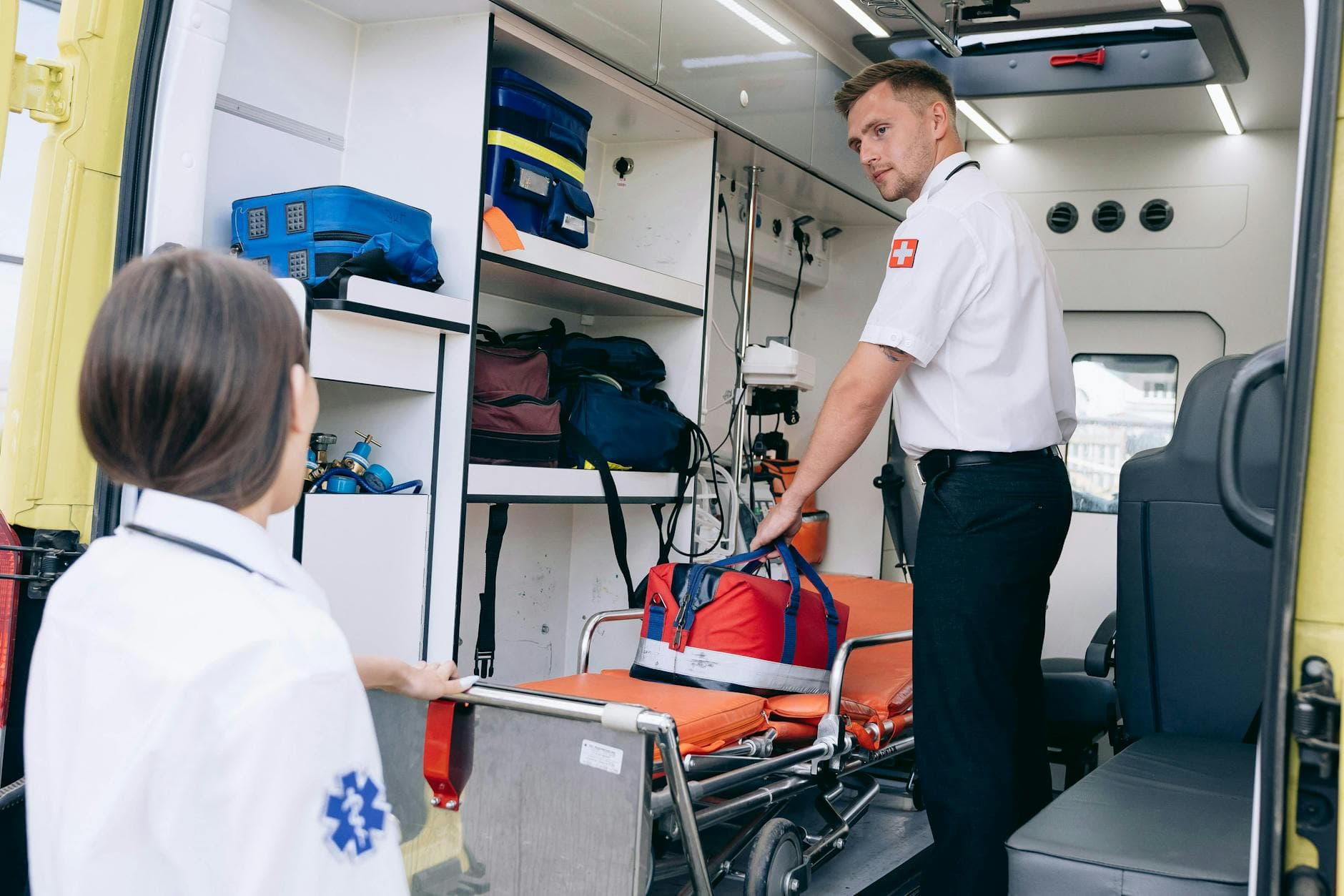 Two paramedics organizing medical supplies in an ambulance for emergency readiness.