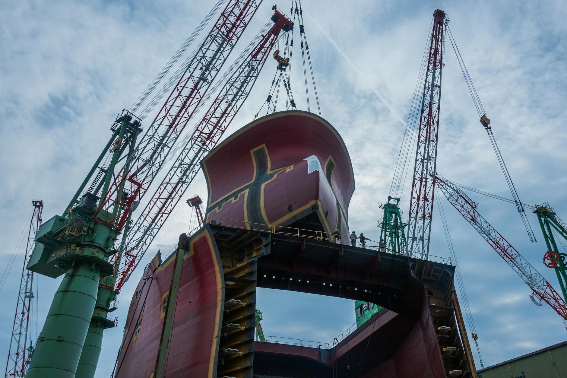 Cranes lift massive ship parts at Onomichi Shipyard, Hiroshima, Japan.