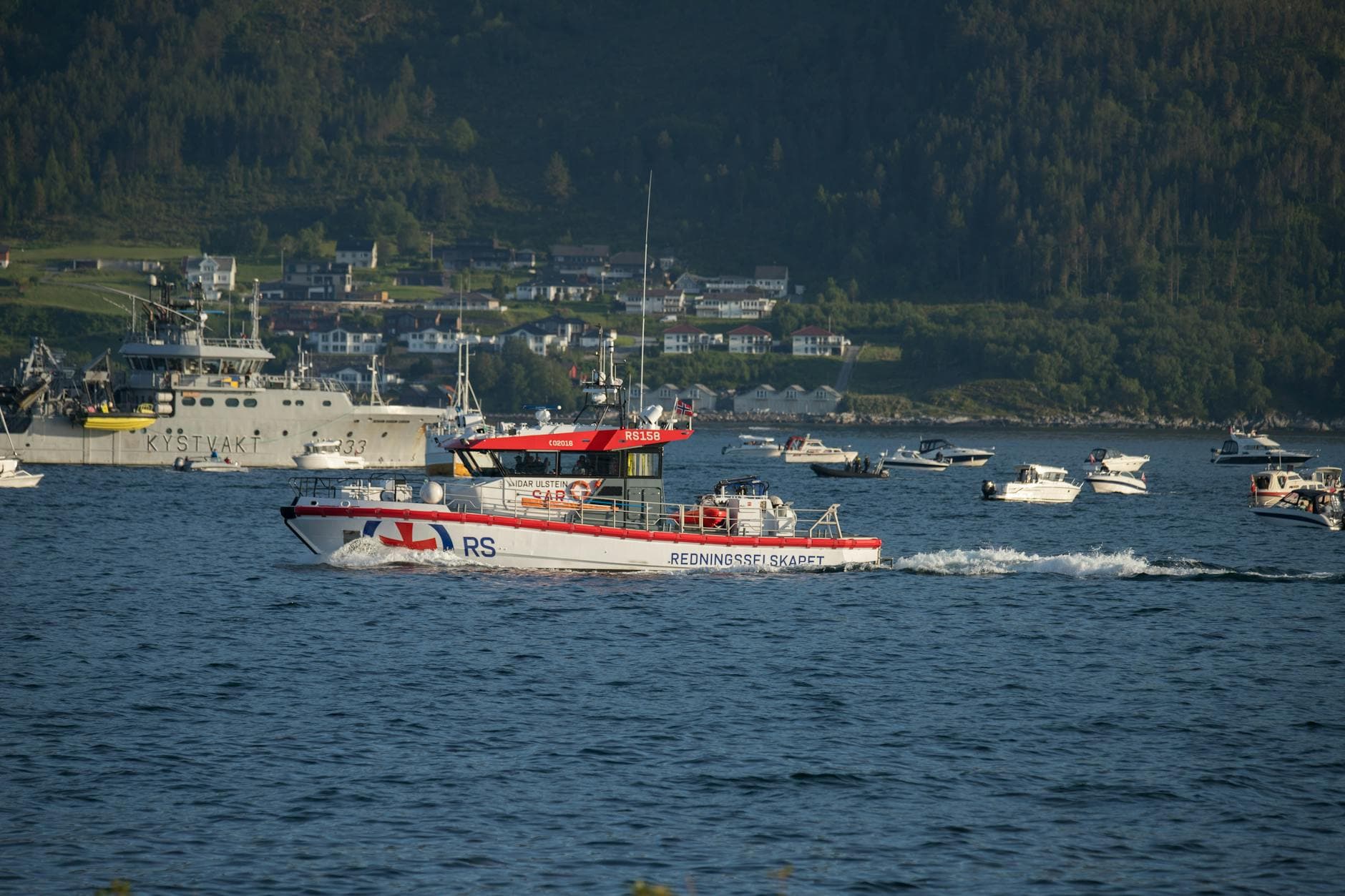 A rescue boat and coast guard vessel navigate the waters of Ålesund, Norway.