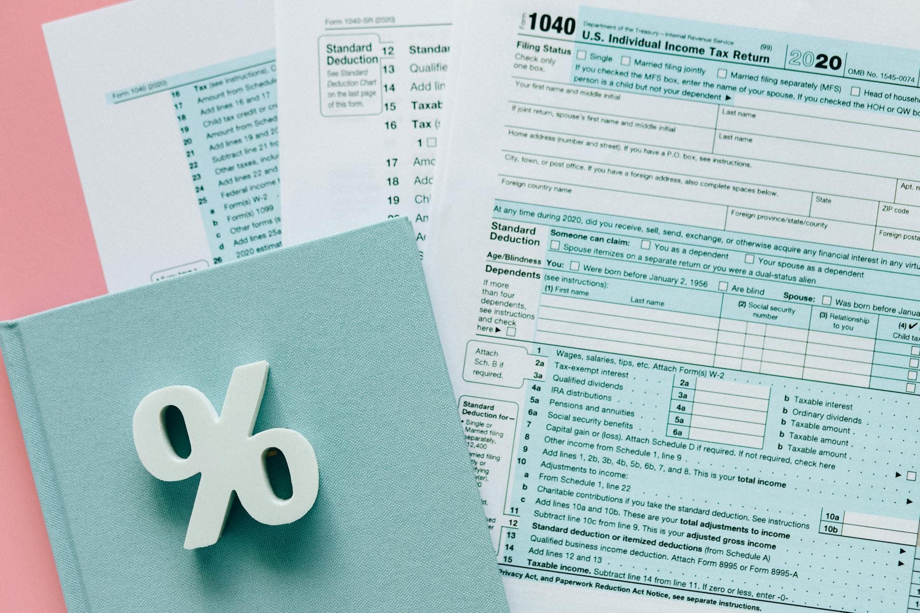 Tax documents with a percentage symbol on a pink and blue desk setup, emphasizing finance.