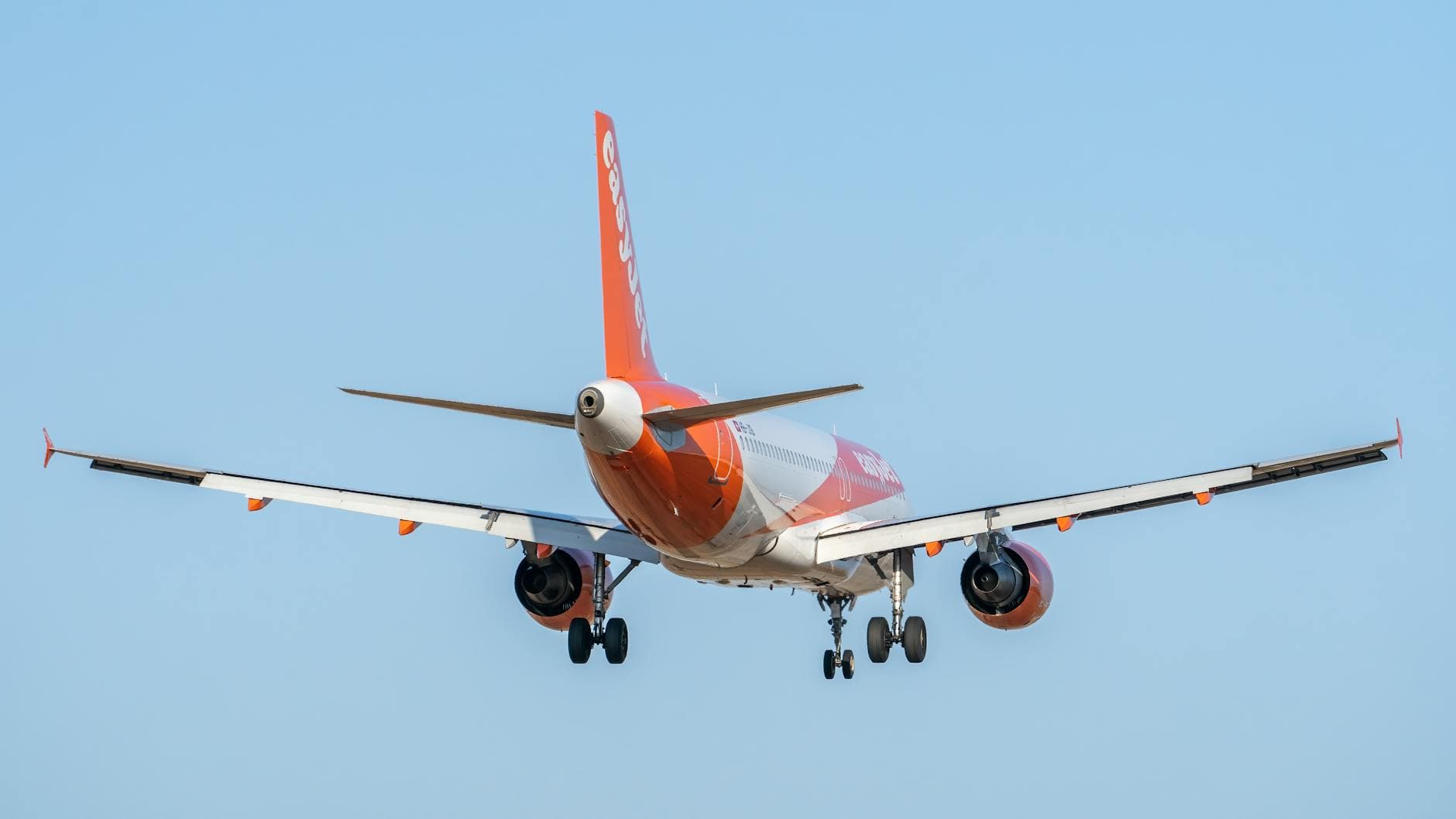 Rear view of an EasyJet Airbus A320 aircraft landing at Valencia Airport, clear sky.