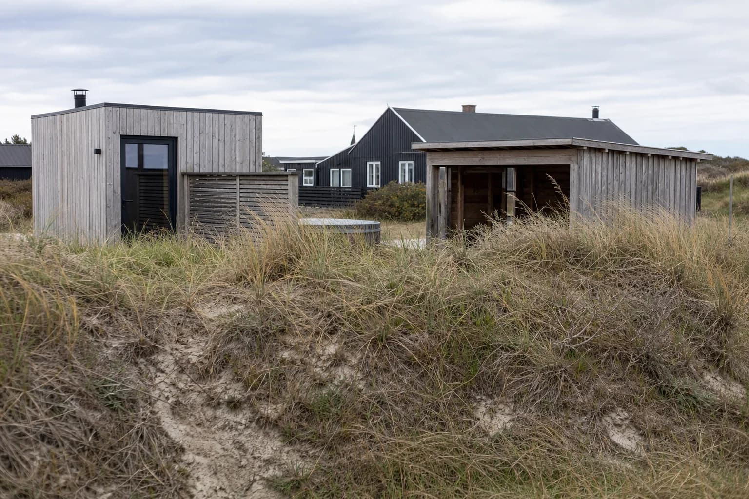 Sommerhus med småbygninger og jordvold i Blokhus.